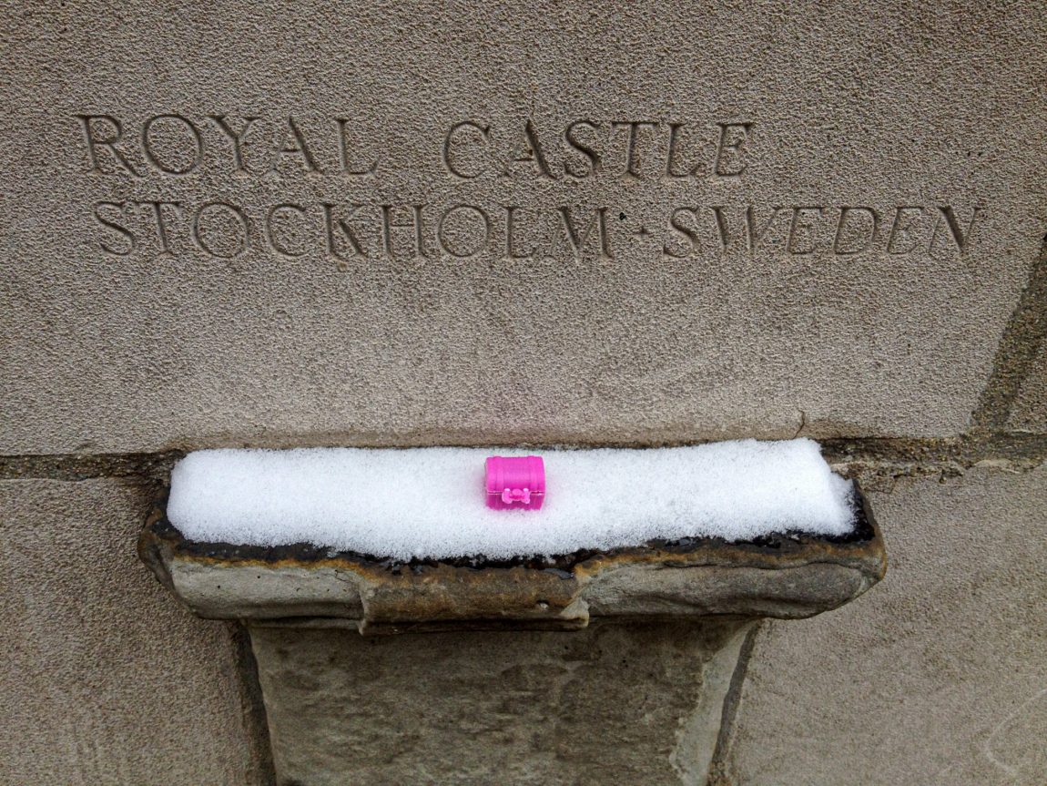 Tiny pink plastic treasure chest sits on a ledge as part of Tribune Tower in Chicago. The ledge is a fragment that came from the Royal Castle in Stockholm Sweden.