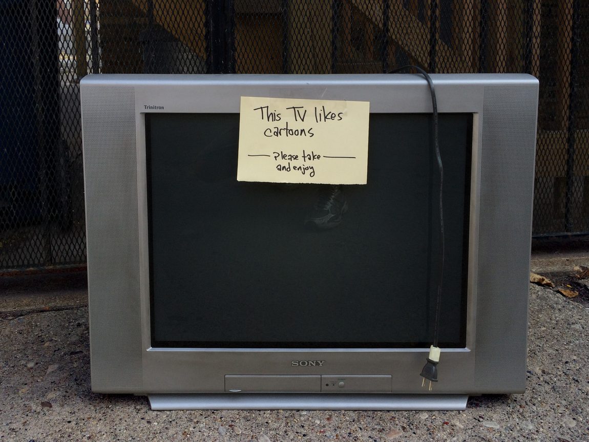 Sony Wega Trinitron 27-inch TV KV-27FS120 sitting in Chicago alley with handwritten sign, "This TV likes cartoons. Please take and enjoy."