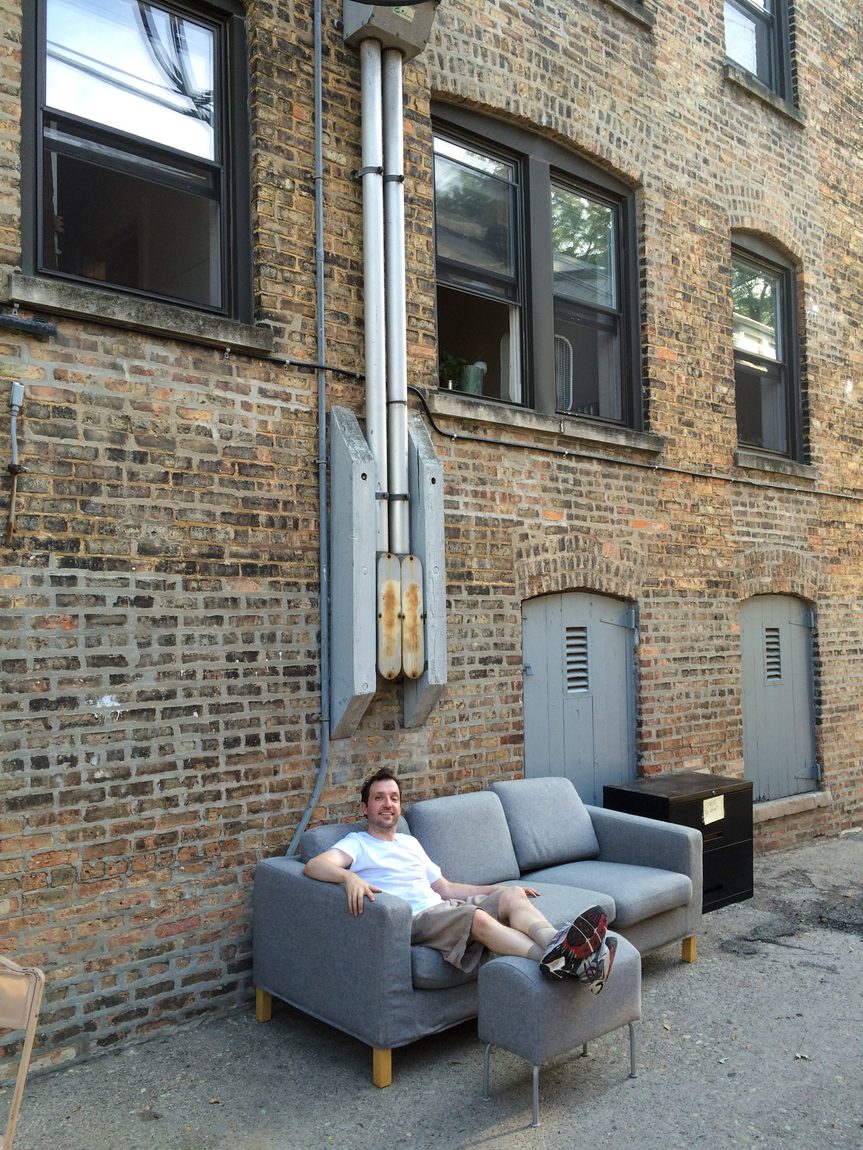 Sitting on my couch in the alley. Placing my couch in the alley with the footrest made it seem like my living room was now in the alley! Here I am resting on my beloved couch that I let go of.